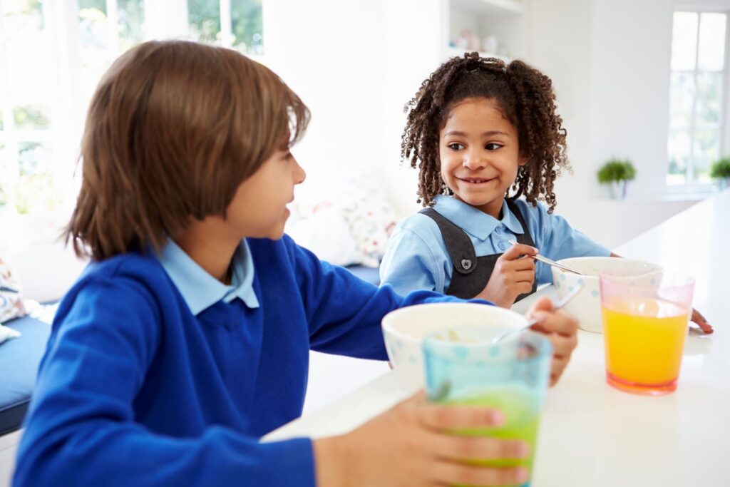 2 children in school uniform eating breakfast food