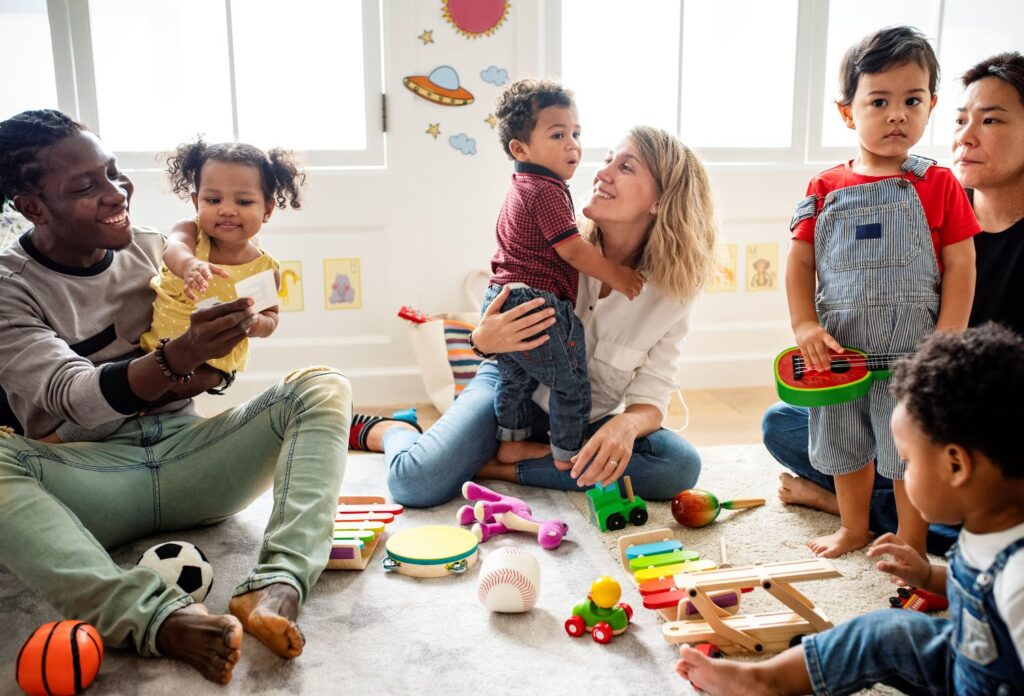 A groups of parents with toddlers sat on the floor in a community hall with toys