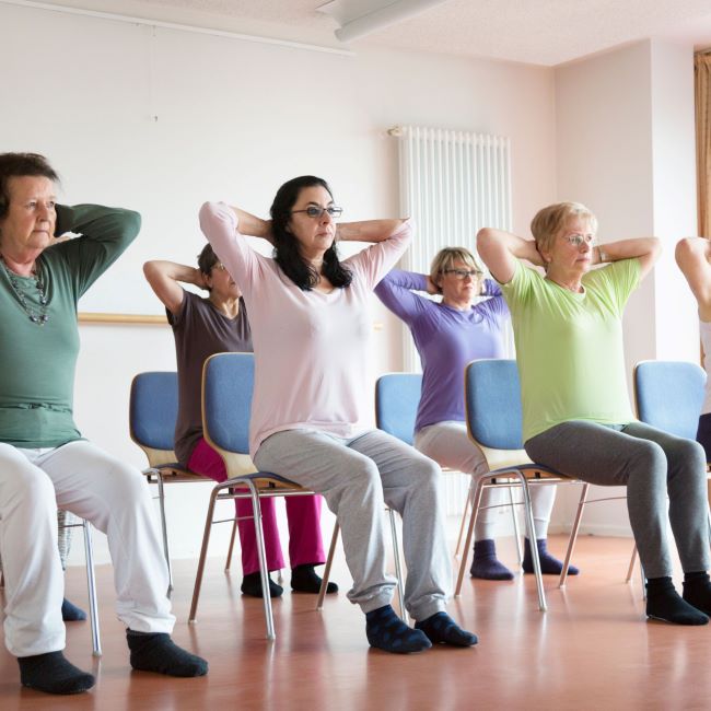 A group of women on rows of chairs doing gentle fitness exercises