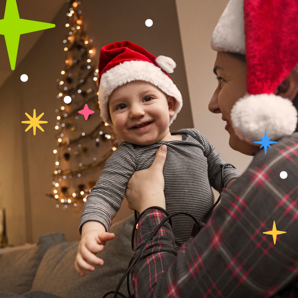 Happy baby in Christmas hat being hugged by mum